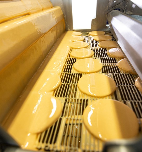 Marel's Active Batter Applicator applying wet coating to formed patties