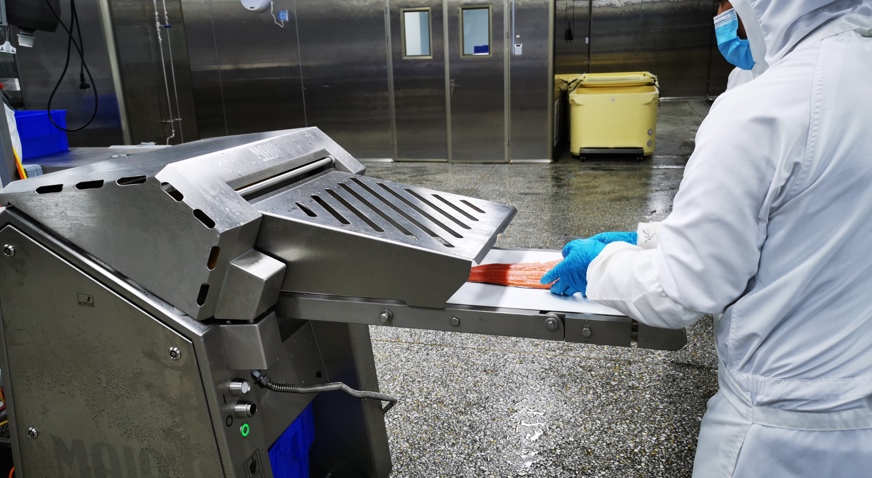 Tianyun employee loads trout into the Maja skinning machine